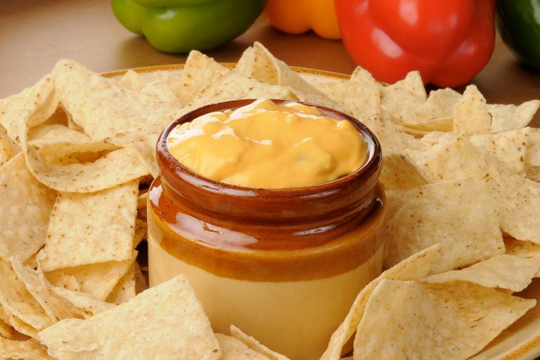 A dip with veggies surrounded by tortilla chips